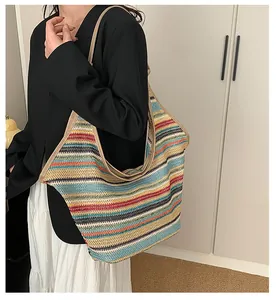 Close-up of a colorful woven straw tote bag with rainbow stripes and beige straps on model
