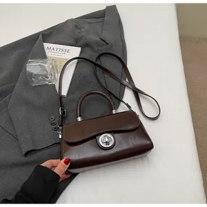 Detail view of a vintage dark brown leather crossbody bag with circular metal twist lock