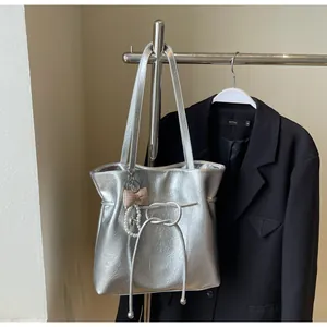 Détail du sac cabas plissé argenté avec nœud, chaîne de perles et breloques