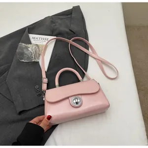 Detail view of pink PU leather handbag on grey blazer with silver turn-lock and handle