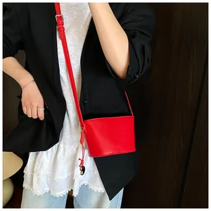 Vue détaillée de la texture du cuir grainé rouge et de l'embossage du sac bandoulière