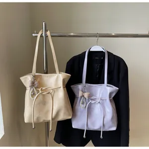 Détail de sacs cabas beige et lilas avec breloques perles suspendus sur un support