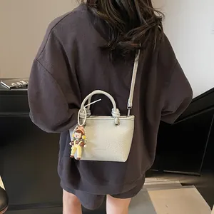 Chic light gray pebbled leather bucket bag with top handles and cartoon charm accessory