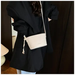Détail de la texture cuir grainé sur ce sac seau bandoulière de couleur crème chic