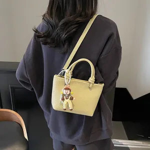 Fashionable pale yellow leather crossbody bucket bag with cute doll charm for women