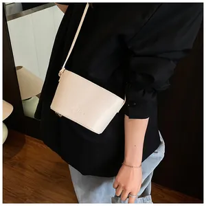 Vue latérale d'un sac seau en cuir grainé blanc cassé porté à l'épaule dans un salon