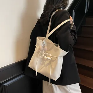 Sac fourre-tout en cuir crème avec nœuds coulissants et breloque en perles