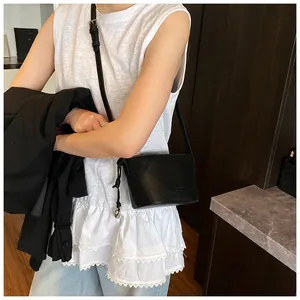 Détail du sac seau en cuir noir avec cordon de serrage et pendentif anneau argenté