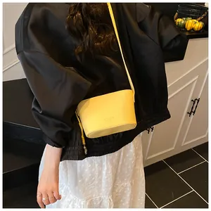 Gros plan d'un sac seau jaune en cuir texturé porté par un mannequin en tenue décontractée