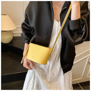 Détail du sac seau en cuir grainé jaune avec lettrage tendance et bandoulière