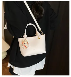 Close-up of cream leather tote bag with litchi texture and cute rabbit charm detail