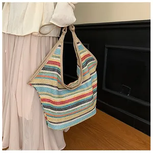 Detailed view of colorful woven straw tote with khaki leather handles and striped texture