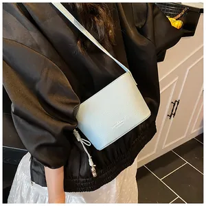 Gros plan d'un sac seau bleu clair à motif litchi avec pendentif en métal et logo