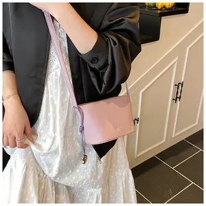 Détail de la texture en cuir rose clair à motif litchi sur un mini sac seau bandoulière