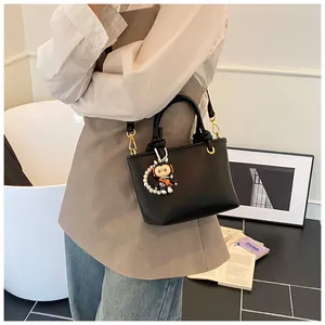 Macro detail of black pebble leather mini tote bag with gold hardware and stylish charm