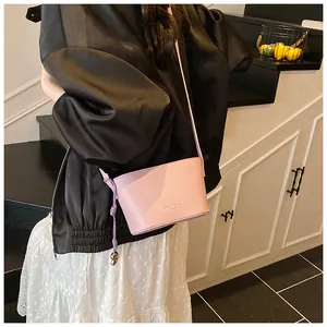Détail d'un sac seau rose en similicuir texturé avec cordon de décoration tissé