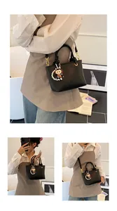 Detailed view of black litchi leather bucket bag with spaceman charm and pearl chain
