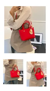 Detail of red pebbled faux leather bucket bag with cute rabbit pendant accessory