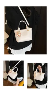 Detail of off-white lychee grain tote bag with gold hardware and cartoon doll charm