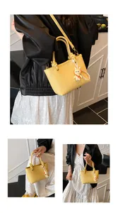 Detail view of yellow lychee texture leather bucket bag with cute bunny and pearl charms