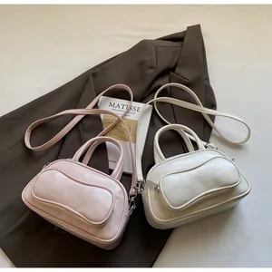 Detail of pink and off-white mini bowling bags with front pocket on a brown blazer