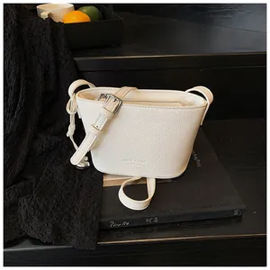 Gros plan du sac seau blanc en cuir grainé avec bandoulière à boucle réglable en métal