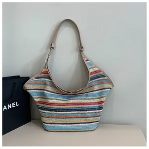 Detail of colorful woven straw tote bag with multi-color stripes and leather shoulder strap
