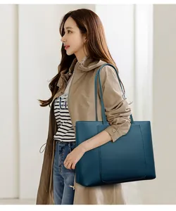 Détail d'un grand sac cabas bleu marine en cuir grainé avec poche frontale porté par un mannequin