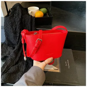 Détail du sac seau rouge montrant la texture grainée et la bandoulière ajustable