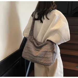 Brown quilted puffer shoulder bag with wavy texture shown on model in warm lighting