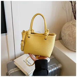 Detail of yellow pebbled leather tote bag with knotted handles and embossed logo