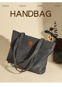 Détail du sac cabas en nylon gris foncé avec un écusson logo en cuir marron