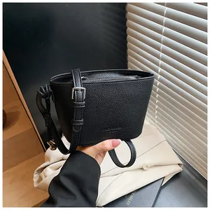 Détail du sac seau noir en cuir à grain litchi avec boucle argentée et fermeture éclair