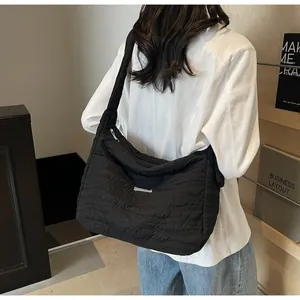 Detailed view of black wave-quilted puffer bag with elegant metallic logo plate