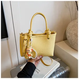 Close-up of bright yellow lychee leather bag with pearl charms and rabbit pendant