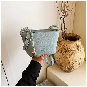 Gros plan du sac seau bleu clair en cuir avec pendentif cœur et bandoulière réglable