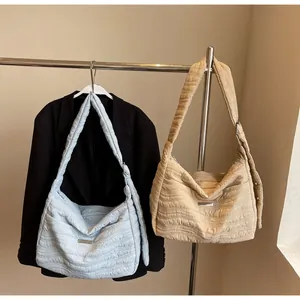 Detail of light blue and beige quilted tote bags with wave texture on metal hanger
