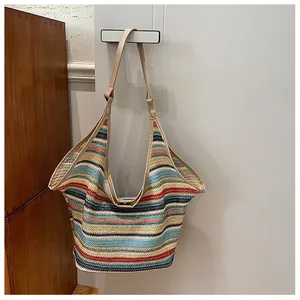Detail of colorful striped woven tote bag with khaki leather straps hanging on a door