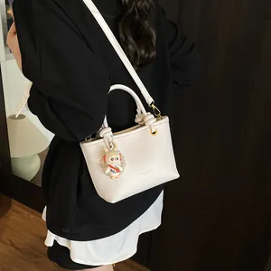 White pebbled leather bucket bag with astronaut rabbit charm for casual commuting