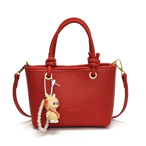 Red pebbled leather bucket bag with top handles, crossbody strap, and cute charm