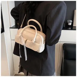 Detail of off-white bowling bag with lace ribbon decor on model in black suit