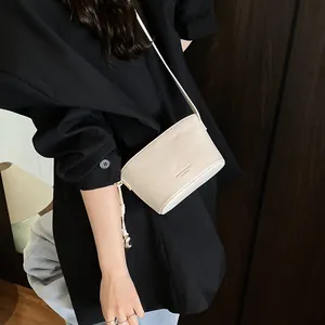 Sac seau chic beige grainé pour femme, style bandoulière avec charme boule en métal