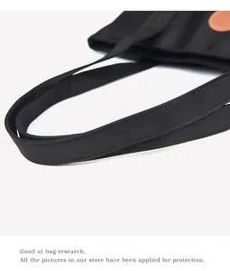 Détail de la couture renforcée et du logo en cuir marron sur le sac cabas en nylon