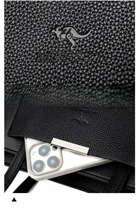 Détail du sac cabas en cuir grainé avec poche avant pour smartphone et logo embossé élégant