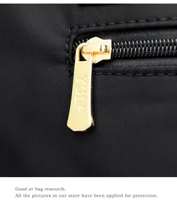Détail d'une tirette de fermeture en métal doré avec logo YGLP sur un sac noir