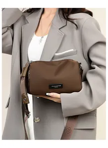 Détail d'un sac de voyage marron en tissu oxford avec large bandoulière sur costume gris