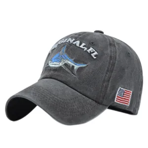 Close-up of shark embroidery and American flag patch on a washed grey cotton baseball cap