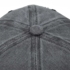Detail of washed cotton baseball cap crown with distressed holes and top button