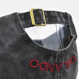 Detail view of washed grey cotton cap with red Orlando embroidery and brass buckle