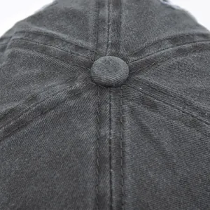 Detail of grey distressed cotton baseball cap crown with stitched panels and top button